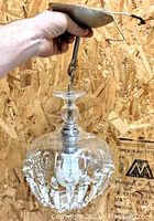 Photo showing the pendant light held up to display its chain, canopy, and the glass body with hanging crystal prisms.