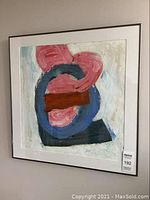 Photo of the full framed abstract painting hanging on a wall, showing the painting's colors and frame.