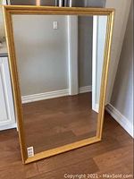 Front view of the large mirror showing the gold frame and clear reflective glass.