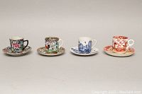 All four demitasse sets arranged in a row showing cup and saucer patterns