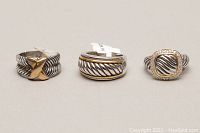 Front view of three rhodium plated 925 silver rings with gold-tone accents and decorative designs.