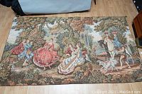 Full view of the tapestry laid flat showing entire Victorian styled outdoor scene with multiple figures, horses, dogs, and classical elements.