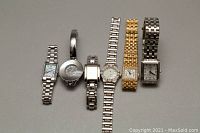 Photo of six ladies watches grouped in one row showing metal bracelets and face styles