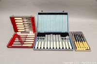 Full shot of three cutlery sets in original boxes showing differing styles and handle colors