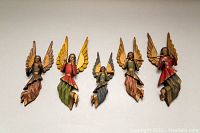 Photo showing all five hand carved and painted wooden angels arranged side by side on white background with good detail of colors and sizes
