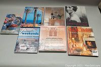 Seven interior design and decor books arranged on the floor, including titles on classic-to-contemporary style, English country, French country, rooms design, and a cooking book titled Gourmet's Weekends, plus The Scented Garden.
