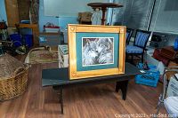 Photo of framed print with wolves on black painted bench in background showing the frame style and artwork detail.