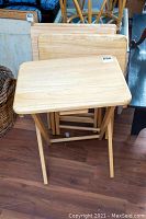 Four wooden TV trays set, one open showing folding legs, others stacked.