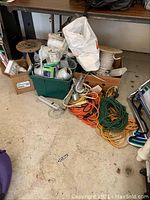 Photo of two large wooden spools with white and blue cable, green bin with light socket housings, multiple extension cords coiled on floor