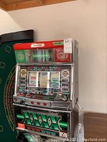 Front three-quarter view of Aruze Continental slot machine showing top light panel, push-button controls, and chrome and green lower panel.