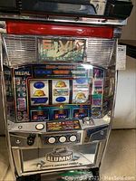Frontal view of chrome slot machine with three-reel display, control buttons and NHL Alumni coin tray