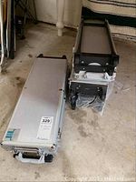 Three aluminum poker cases stacked on garage floor, two closed and one partially wrapped in bubble wrap.