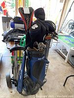 Full view of Top-Flite bag loaded with clubs and attached push cart in garage setting