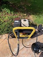 Overhead front view showing white fuel tank, red engine housing, yellow frame and coiled hose