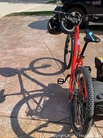 Front-side view of red Aggressor Sport mountain bike with two helmets on ground