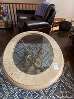 Top view showing oval beige marble rim and clear glass center over patterned rug