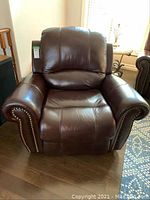 Front view of recliner showing padded seat, back and rolled arms with nailhead trim