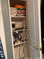 Closet with stacked towels, crutches, and box of facial tissues on shelves