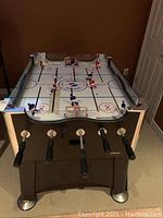 Front and top view of table hockey game showing play surface, player rods, and goals
