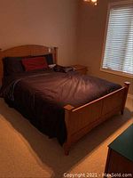 Front view of full bed setup showing headboard, mattress with navy bedding and red pillow