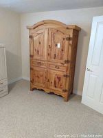 Front view of armoire showing arched top, panel doors, drawers and base.