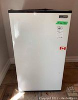 Front view of white Danby mini fridge with black top edge and stickers on door.
