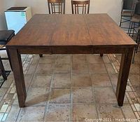 Full top-down view of square table showing wood grain and removable leaf seams.