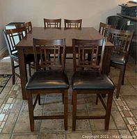 Overview of eight dark wood bar stools arranged around a table