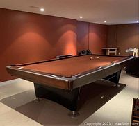 Full view of brown-felt pool table in basement setting