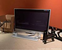 Panasonic 40" Viera TV on stand with remote and wall mount beside it.