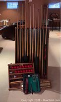 Overview of cue rack with cues, ball rack with balls and chalk, travel case and scorekeeper