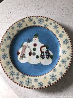 Ceramic plate with snowman figures and snowflake designs on rim