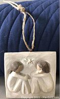 Willow Tree Friendship plaque showing two carved figures connected by a twine string for hanging.