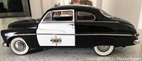Black and white 1948 Mercury Police Car model with police badge on door and whitewall tires