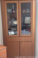 Front view of the Danish Modern teakwood corner cabinet with glass doors showing shelves inside with display items (not included).