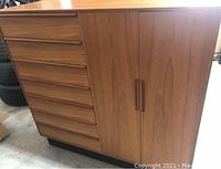 Front view of Danish modern teakwood chest/dresser showing seven drawers on left and closed two-door cabinet on right.