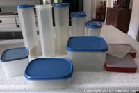 23 translucent Tupperware containers with blue lids of various sizes arranged together showing quantity and condition