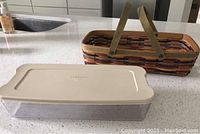 2009 Bittersweet Bread Carrier basket with beige snap-on plastic container and lid, seen on a kitchen countertop.