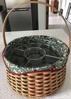 Woven basket with mixed natural and colored weaving, floral fabric liner inside, clear plastic protector insert with compartments inside, tall wood handle.