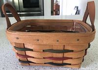 Close-up of tea basket with wooden protector and handles, showing natural wood with green and dark red woven accents.
