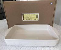 Ivory colored Longaberger Woven Traditions 9x13 baking dish with woven pattern handles displayed in front of original box