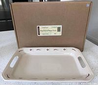 Rectangular handled ceramic platter with red painted woven tradition style detailing in front of its box labeled Longaberger Woven Traditions handled platter red.