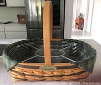 Large rectangular woven wooden basket with single handle, green plaid fabric liner, and clear divided plastic protector inside.