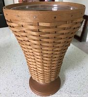 Clear photo showing full basket with woven wood, metal rivets, pedestal base and clear two-piece plastic protector inside the basket top.