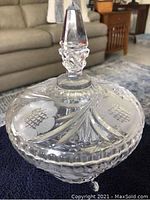 Heavy lidded candy dish with large faceted glass stopper and decorative cut glass pattern on the body.