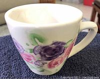 Tea cup with handle showing floral pattern in pink, purple and green