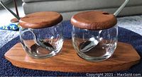 Danish modern teak condiment set with two clear glass jars featuring teak lids and spoons on a teak tray.