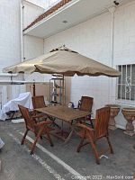 Full setup showing teak table, four chairs and beige umbrella open