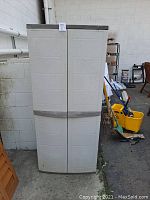Front view of closed outdoor plastic storage shed with beige doors and dark trim