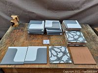 Wide view showing stacks of vintage fired clay tiles in two styles and one plain terracotta tile, placed on wooden surface.